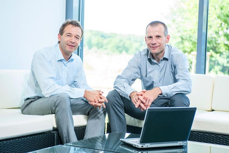 Andreas Scher und Birger Bösel sitzen auf ein Rattanmöbeln im Foyer von PLANET IC